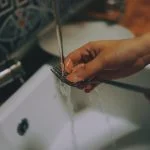 mano fregando un tenedor sobre fregadore